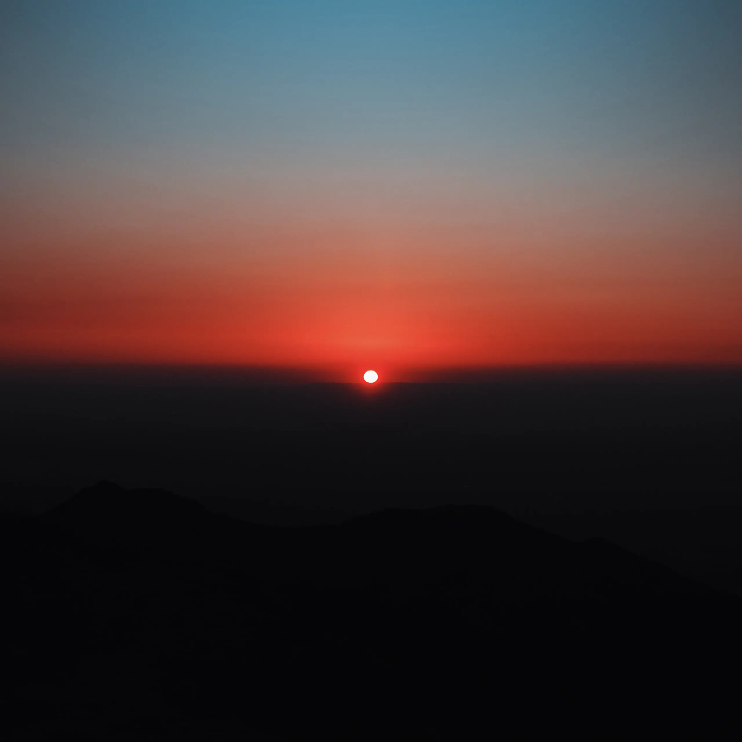 The sun breaking the horizon over a dark ridgeline