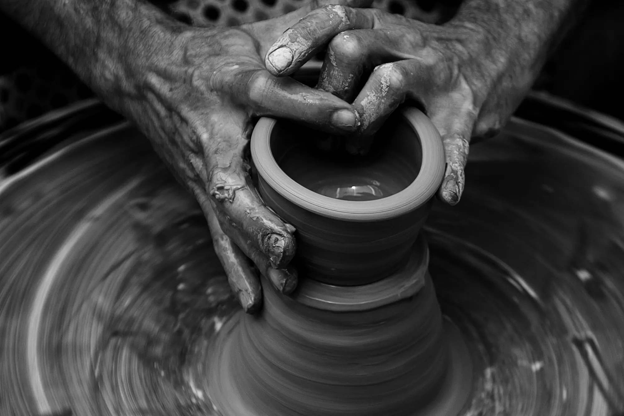 A pair of hands shaping clay on a turning wheel
