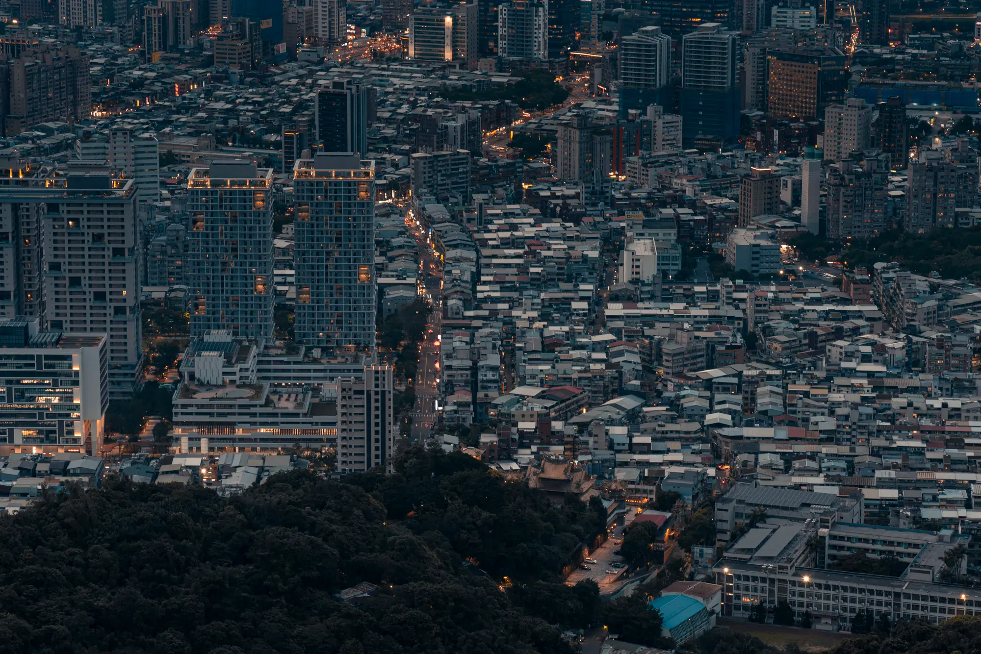 A city at dusk seen from above, lit street by street